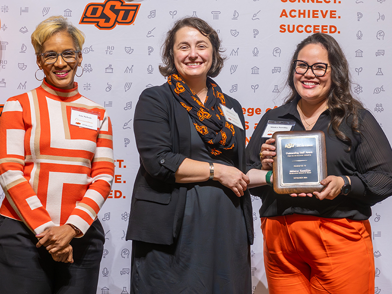 Winner Monica Santillan holding her award on stage with Dean Cro