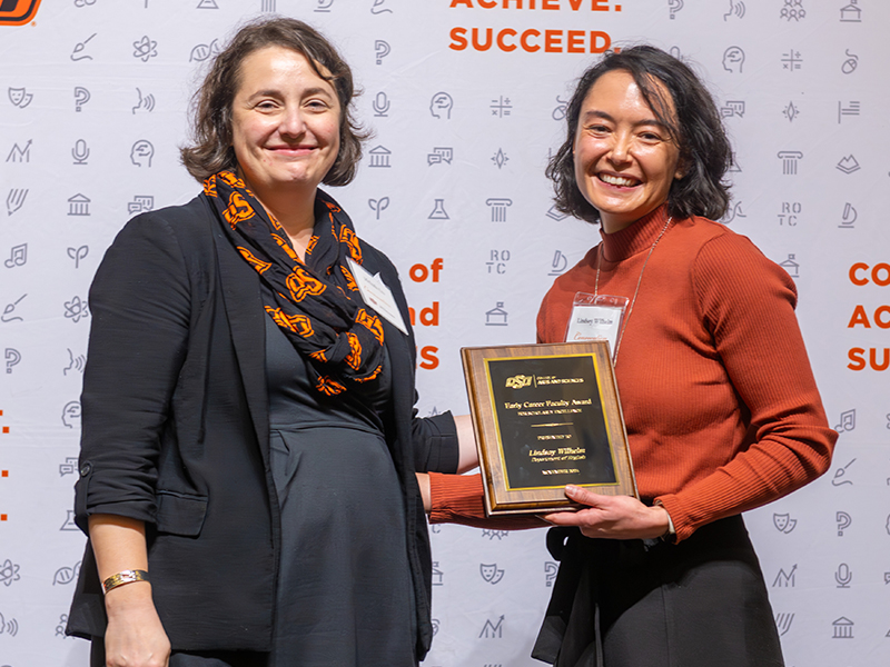 Winner Lindsay Wilhelm holding her award on stage with Dean Cro