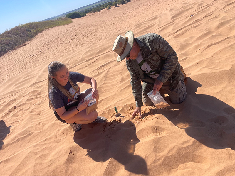 Scooping sand into baggie in the Gloss Mountains