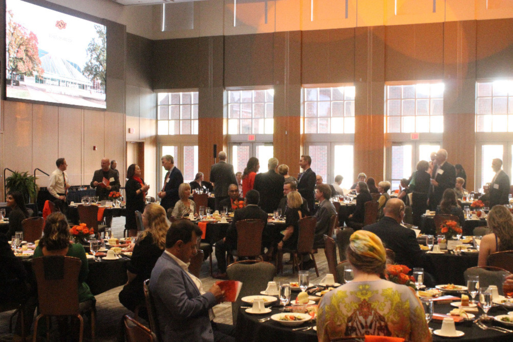 The banquet hall full of people standing and visiting before the meal. The banquet hall full of people standing and visiting before the meal.