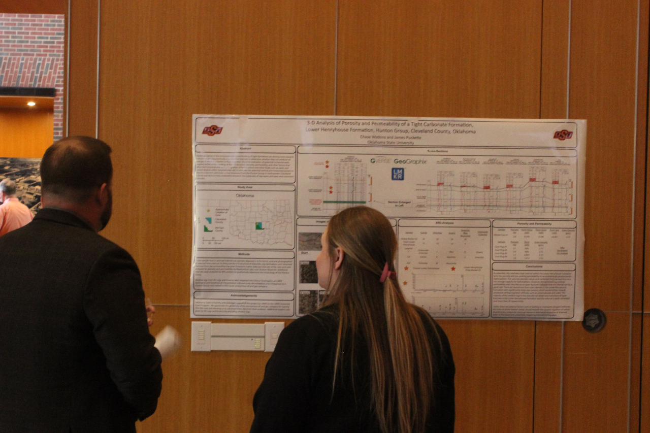 A female student showing a male alumni member her presentation poster. A female student showing a male alumni member her presentation poster.