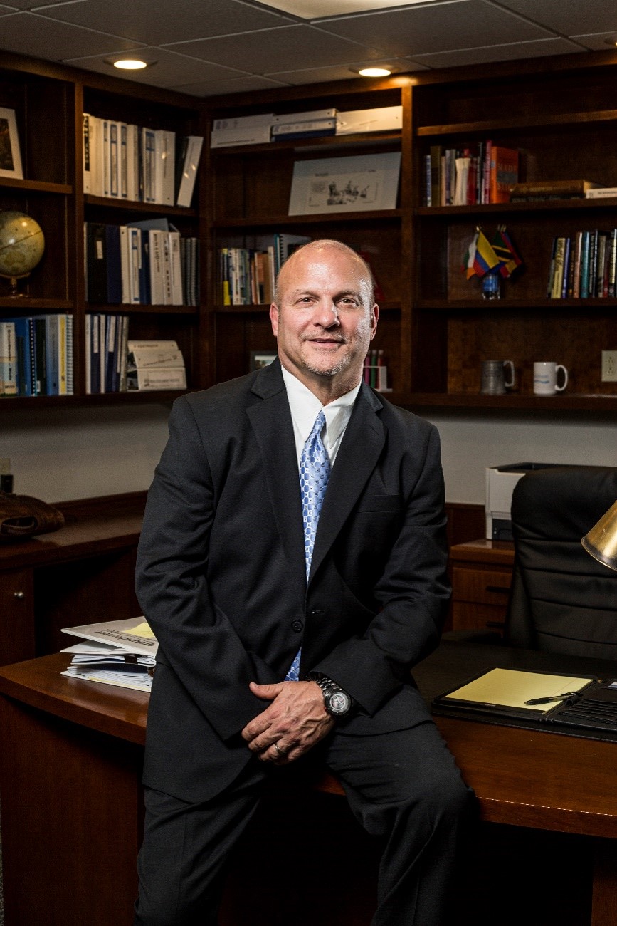 Mr. Terry Morse sitting on a desk in his office posing for a photo. Mr. Terry Morse sitting on a desk in his office posing for a photo.