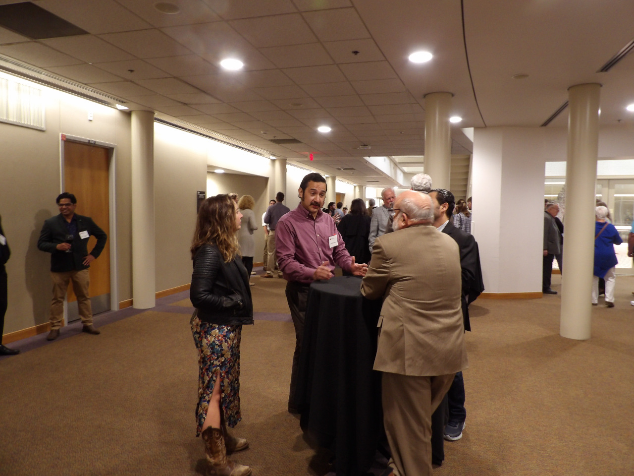 Three males and one female visiting in banquet hall before banquet begins. Three males and one female visiting in banquet hall before banquet begins.