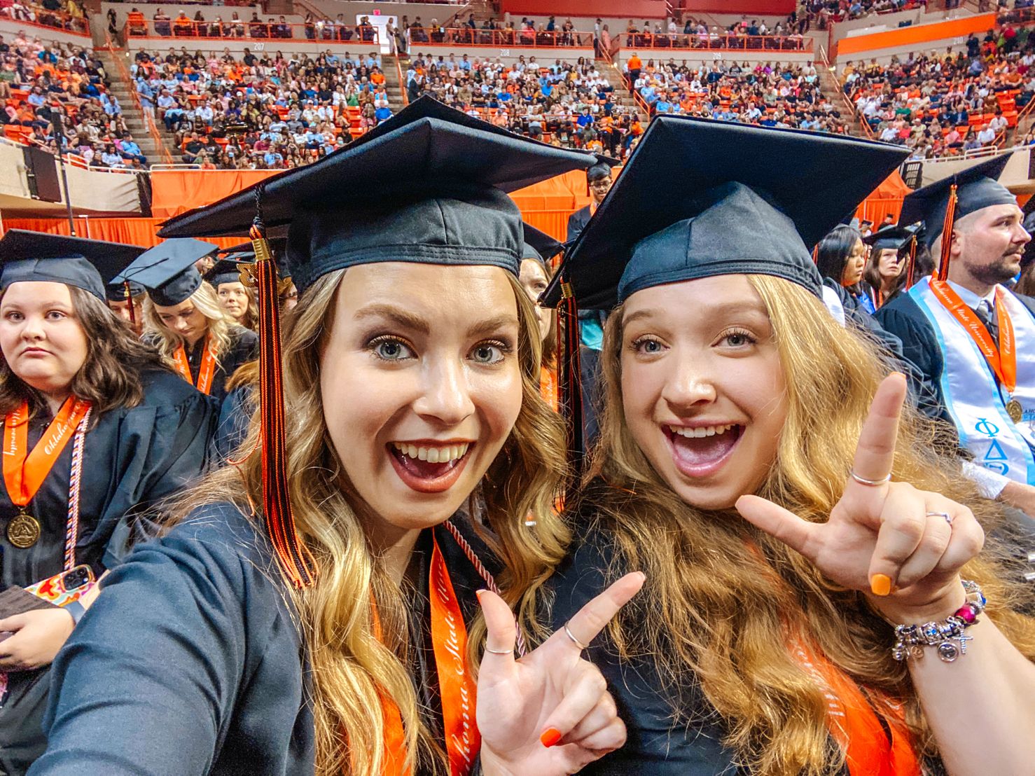 Megan Garret and Izabelle Buentello wearing cap and gown at graduation posing together for a photo Megan Garret and Izabelle Buentello wearing cap and gown at graduation posing together for a photo