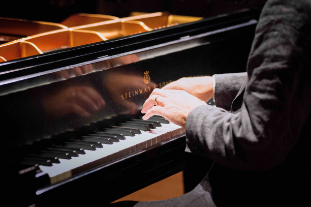 two hands playing a piano