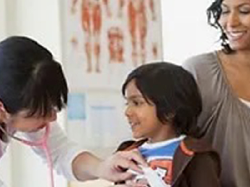 Doctor examing a boy with mom looking on