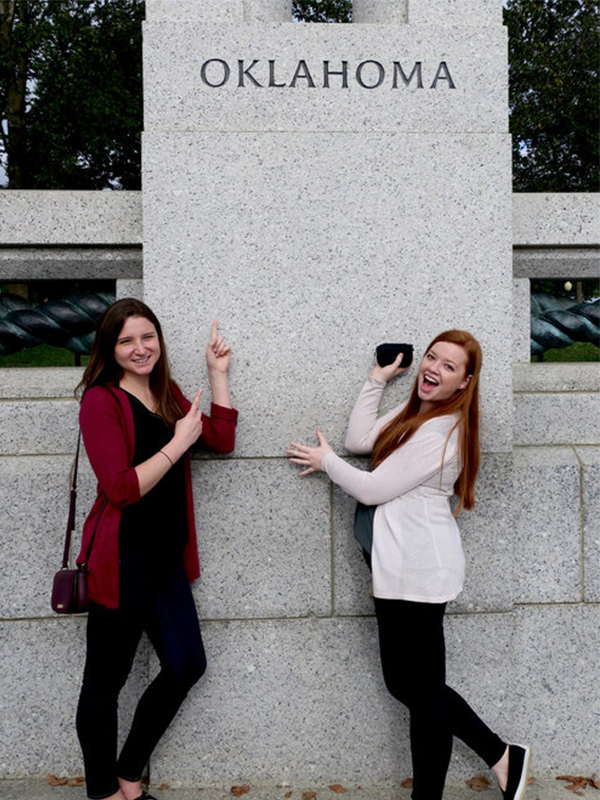 Two female students in front of an Oklahoma Sign at the International Society of Paediatric Oncology Conference