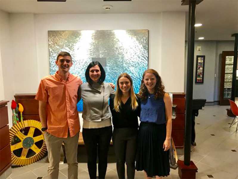 Four students with arms around each other smiling at camera