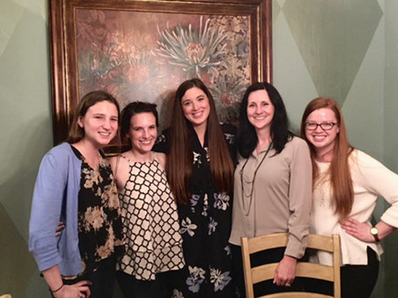 Five female students with arms around each other smiling at camera