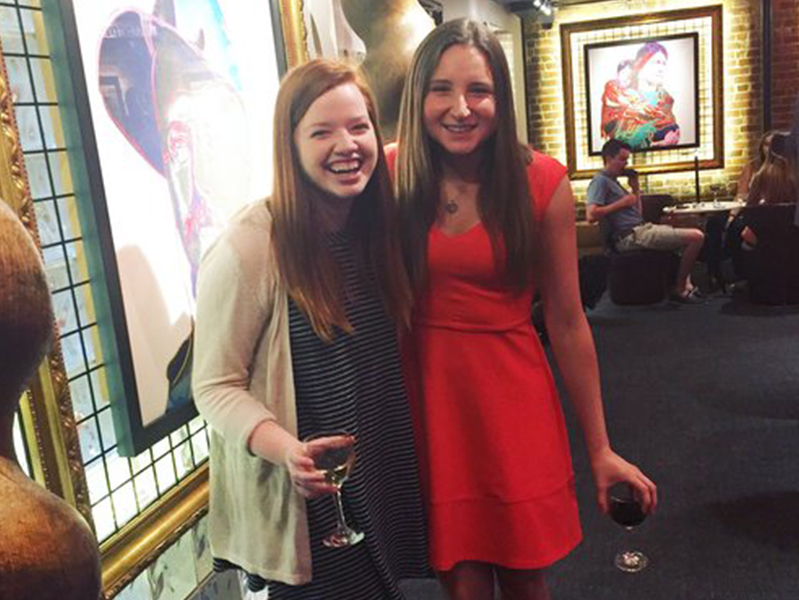 Two female students with arms around each other smiling at camera