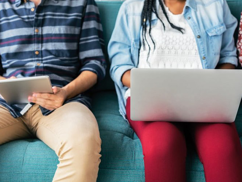 man holding a iPad sitting next to a woman with a laptop