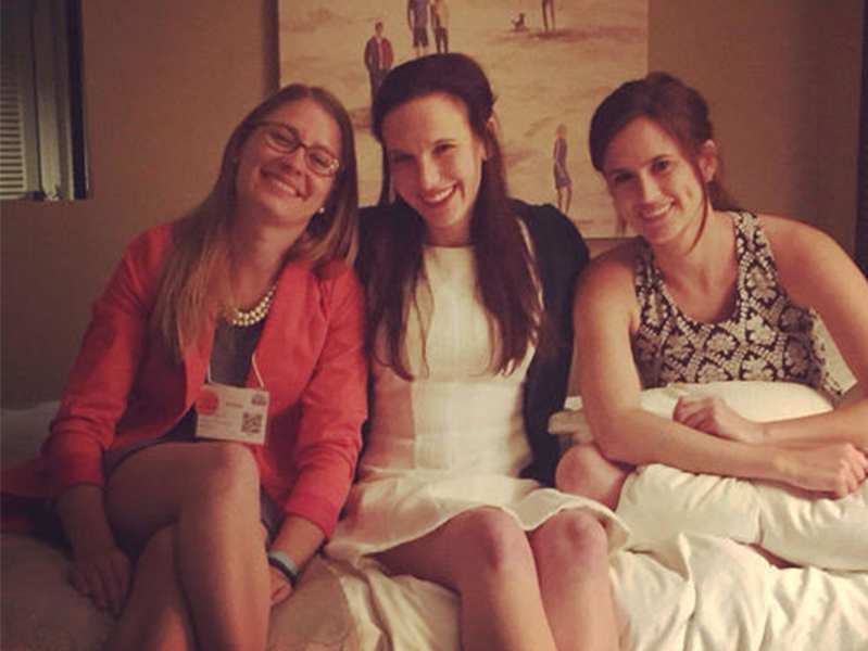 Three females sitting on a bed smiling for the camera at the Society of Pediatric Psychology Annual Conference