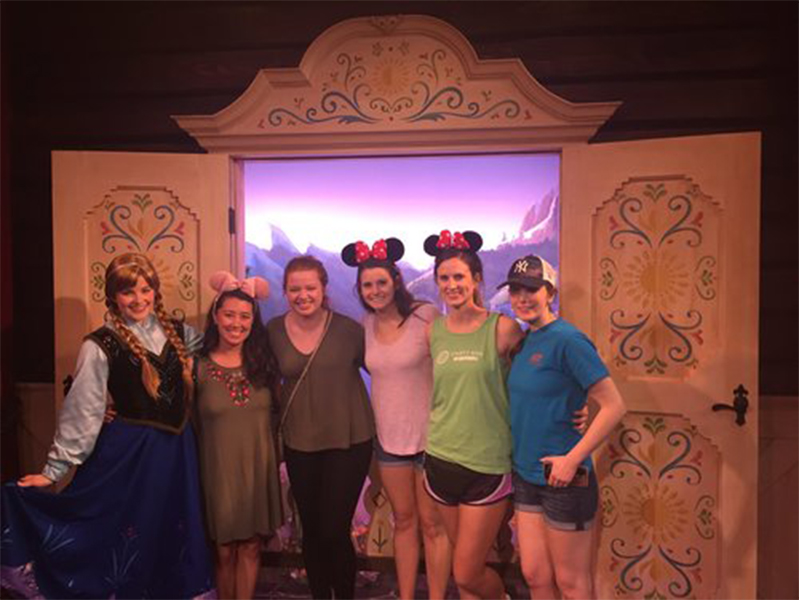 Five female students posing with Anna at Disney