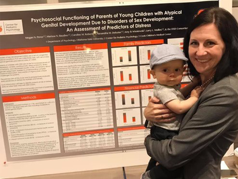 Baby and female student in front of poster at the Society of Pediatric Psychology Annual Conference
