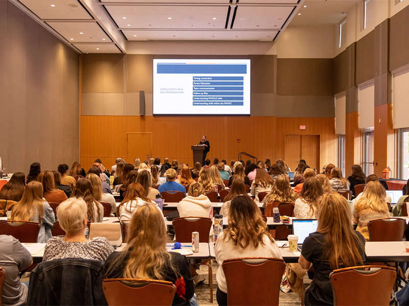 A group of students sitting in a classroom, listening to the instructor.