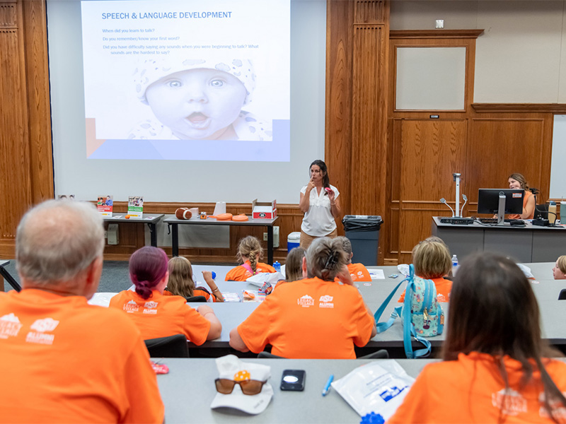 A presentation on baby speech and language development at the university, with grandparents listening attentively.