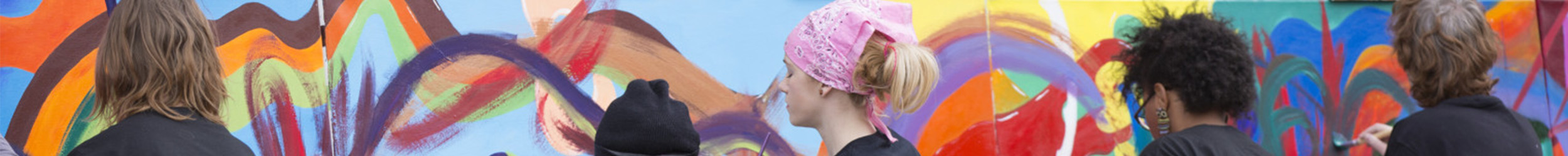 Group of students painting a colorful mural on an outdoor wall